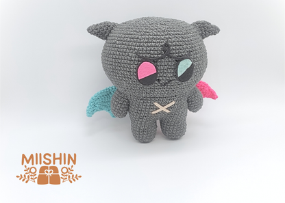 Vista lateral del amigurumi Kkamyo mostrando alas bicolor, azul y rosa.